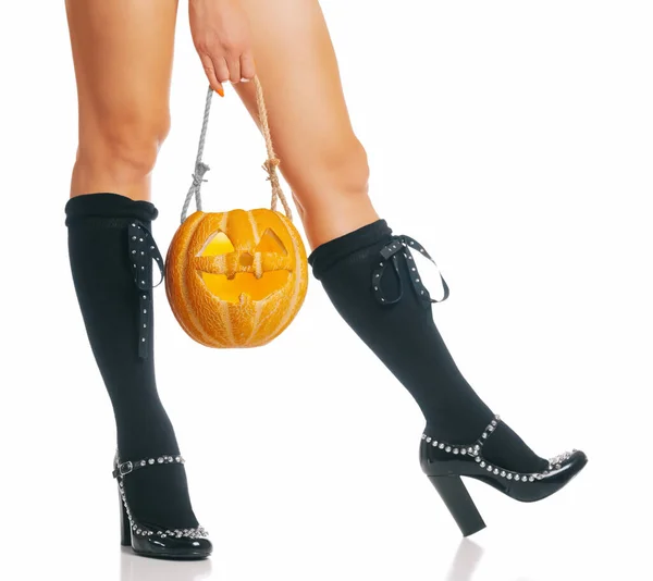 Strega di Halloween con zucca intagliata vicino alle gambe . — Foto Stock