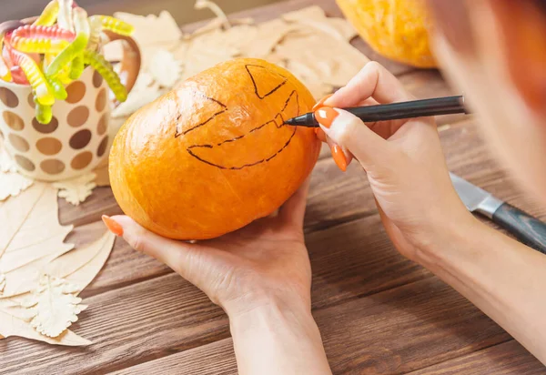 Woman’s hands drawing a face sketch on pumpkin. — Stock Photo, Image