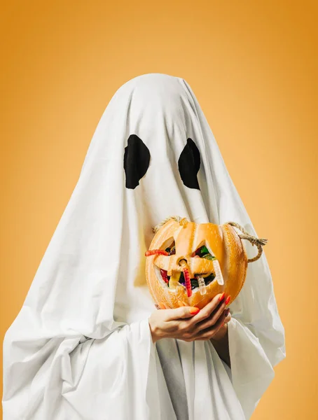 Geist hält Kürbiskorb mit Süßigkeiten zu Halloween. — Stockfoto