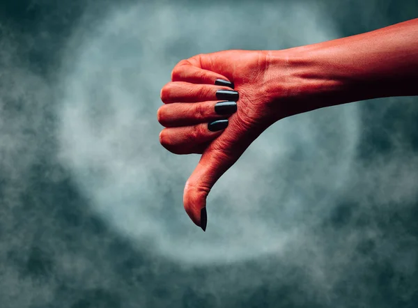 Red hand of a devil with thumb down gesture. — Stock Photo, Image