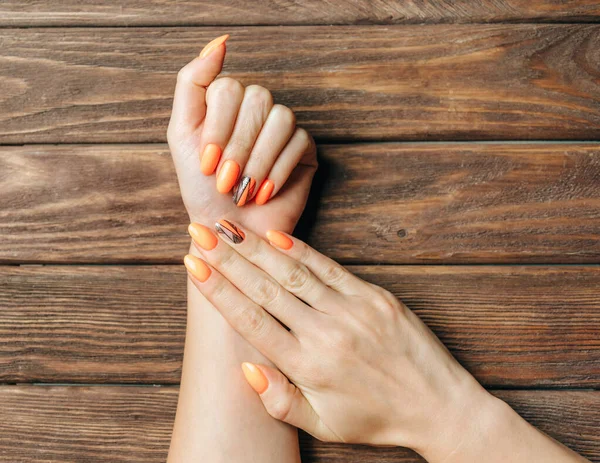 Manos femeninas jóvenes con hermosa manicura de color naranja . —  Fotos de Stock