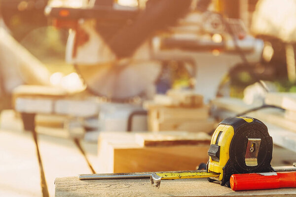 Measuring tape in front of electric saw in workshop.
