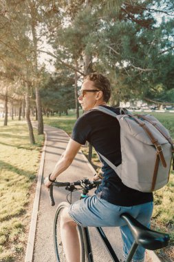 Yeşil yaz parkında bisiklet süren sıradan bir genç adam..