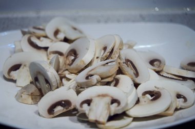 Mutfakta yemek pişirmek için hazırlanan tabakta taze dilimlenmiş mantarlar