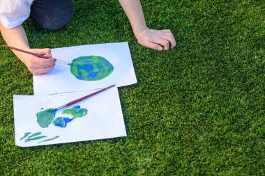 Kapalı çocuklar, Dünya 'nın bir resmini çiziyor. Fırça ve boyayla çocuk resmi. Dünya günü, plastiksiz ve sıfır atık kavramı..