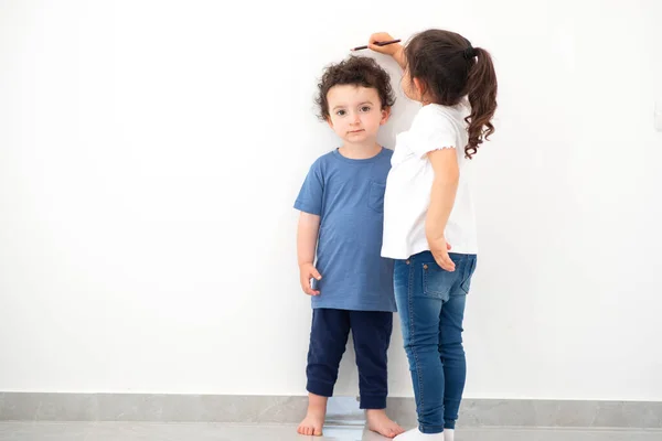 Hermana feliz mide el crecimiento del hermano . — Foto de Stock