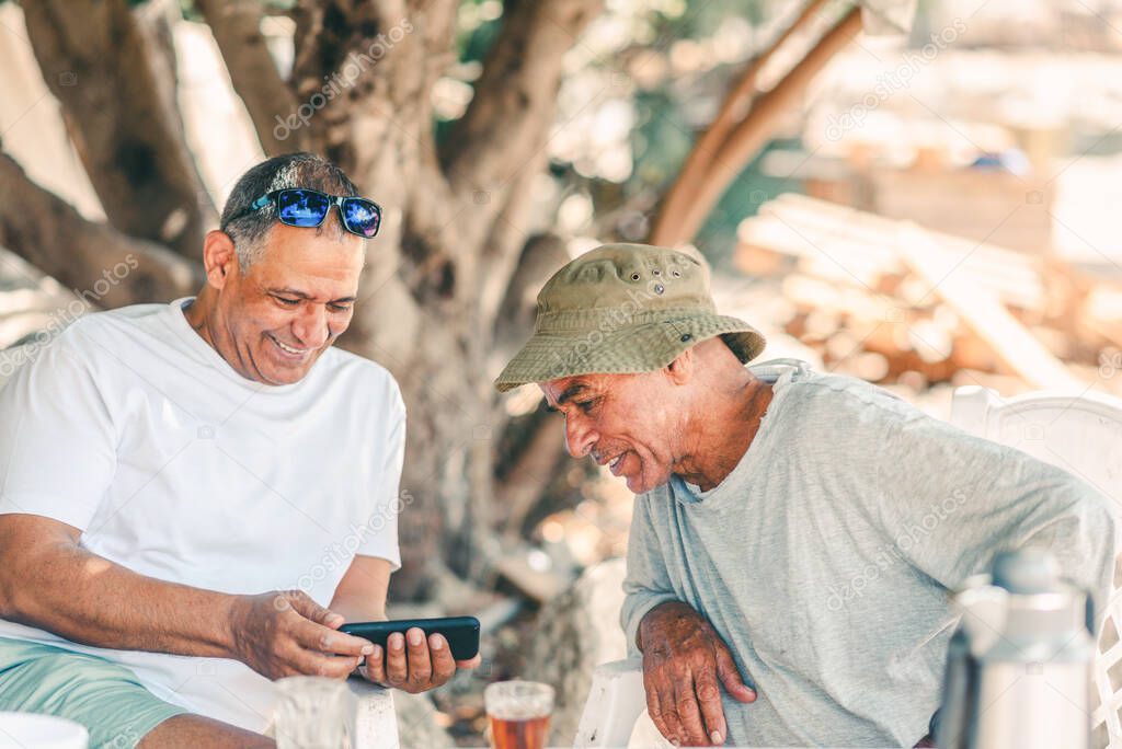 Two Happy Senior Men Baby Boomers Friends Having Fun using smartphone. Active And Healthy Lifestyle.