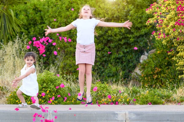 Маленькі дівчата кидають рожеві пелюстки над головою — стокове фото