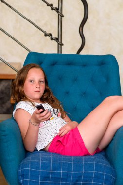 Koltuğunda oturan genç kız televizyon izliyor..