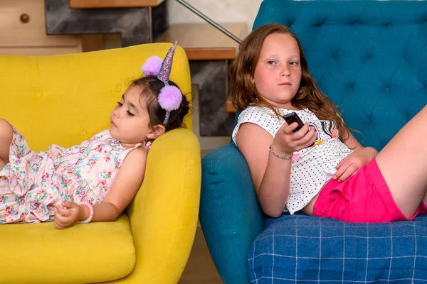 Siblings lying on the armchair watching tv together. — Stock Photo, Image