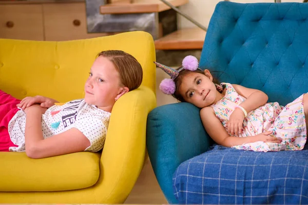 Siblings lying on the armchair watching tv together. — Stock Photo, Image