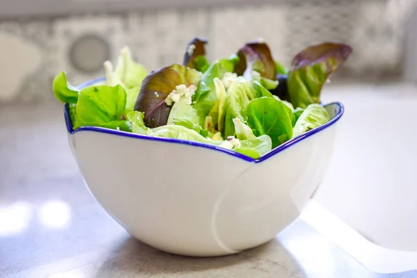 Schüssel mit frischem Salat auf Marmortisch in der Küche. — Stockfoto