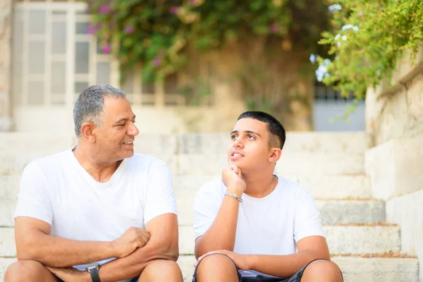 Glücklicher Teenie-Junge ruht auf Treppe sprechen mit älterem Vater genießen Freizeit Familienwochenende. — Stockfoto