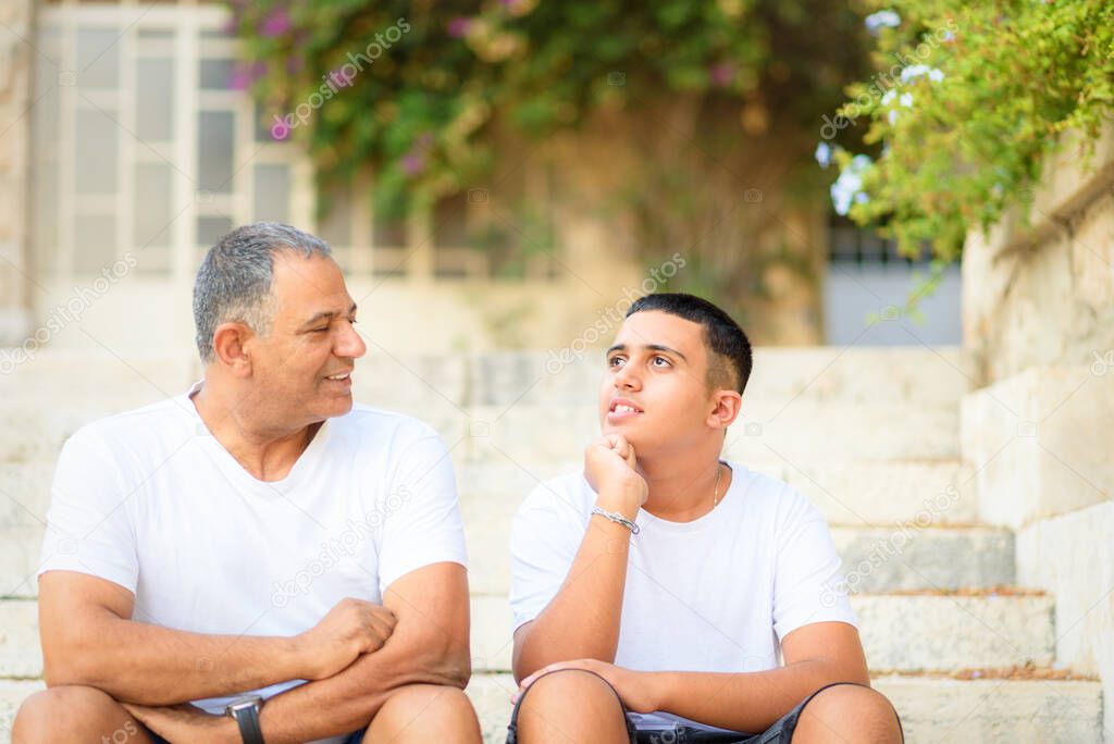 Happy teen young boy rest on stairs speak with elderly father enjoy leisure family weekend.
