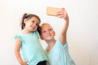 Mutlu çocuklar selfi yapıyor. İki sevimli kız kardeş kendi fotoğrafını çekiyor..