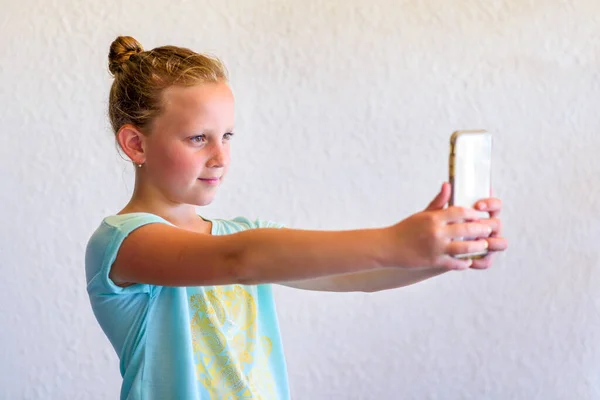 Дівчинка-підліток обирає сельфі. Portrait of Stylish Girl In Neo Mint Color T-shirt Using Smartphone. — стокове фото