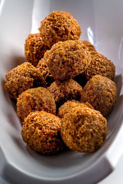 Beyaz arka planda falafel topları. Falafel geleneksel bir Orta Doğu yemeğidir ve genellikle pitte servis edilir..
