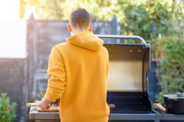 Bağımsızlık Günü 'nde arka bahçe bbq, Yom Haatzmaut. Mutlu genç adam bir evin bahçesinde barbekü yapıyor..