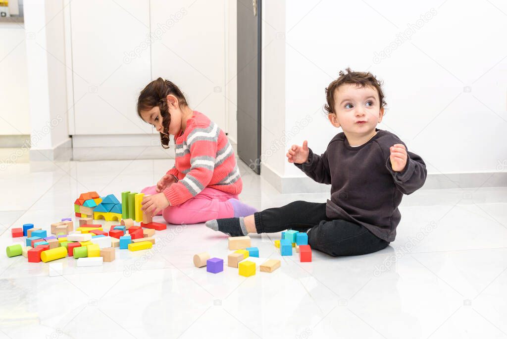 Happy children play with zero waste toys. Sibling creative children building from wooden blocks in home during coronavirus.