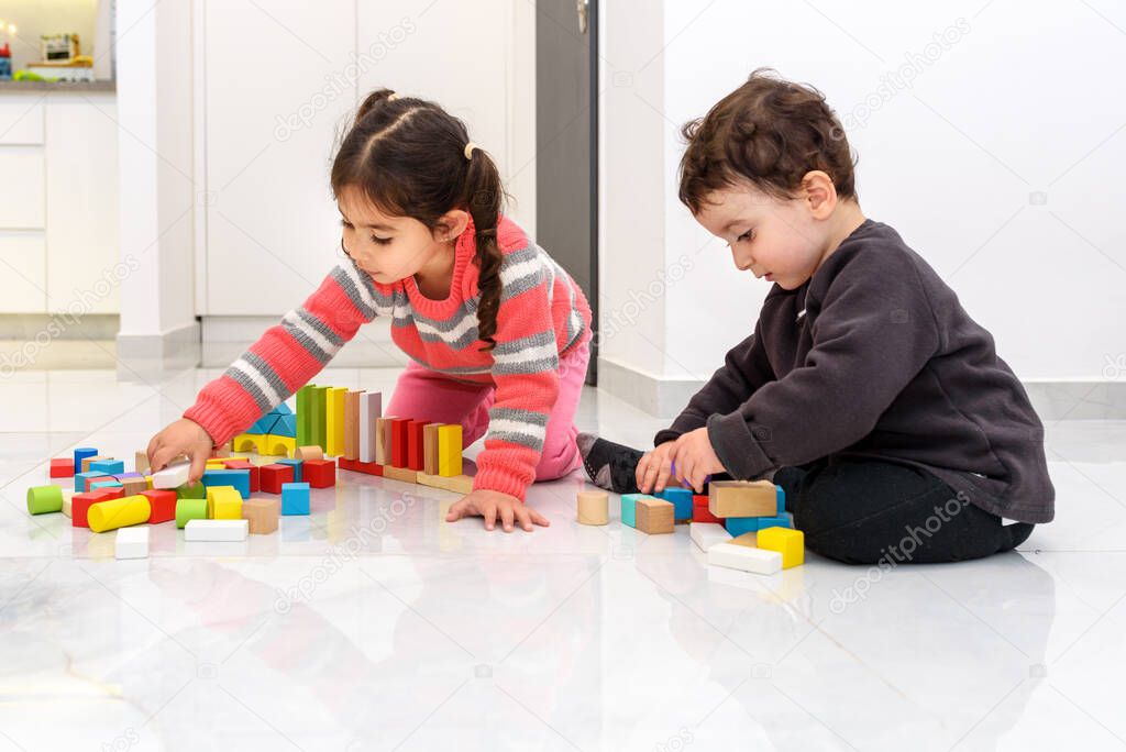 Happy children play with zero waste toys, different color and shape wooden toy blocks.