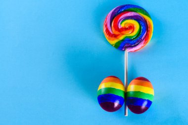 Lgbt ailesi. Lgbt bayrağı renginde yumurta ve mavi arka planda gökkuşağı lolipopu. Eşcinsel çiftlerin çocuk evlat edinmesi ve büyütmesi için yaratıcı bir fikir. Gay yaz partisi.