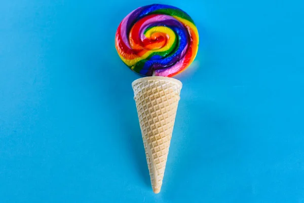 Rainbow candy in ice cream wafle cone on blue background.Colorful lollipop. LGBT, Party, summer, happy lifestyle concepts.