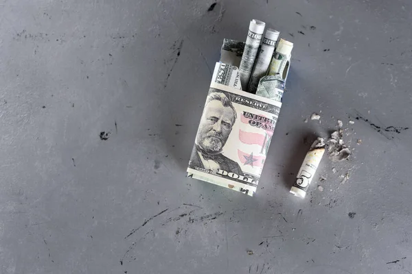 Package of cigarette filled with paper money dollars banknote and Cigarette butt. Smoking is bad for your health, actually burning or wasting money.World No Tobacco Day. Top view.