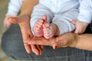 Torunu olan mutlu bir büyükanne. Son sınıf öğrencisi kadın şirin pembe bebek ayağını içeride tutuyor. Aile tatlı anları.