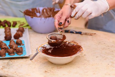 Yemek pişirme konsepti. Çikolata yapan genç bir kadın. Tatlı hazırlayan genç bir kızın ellerini kapar, çikolatalı mantarı kakao tozuyla parlatır..
