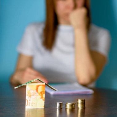 İsrail para birimlerinden manken evi olan orta yaşlı kadın tahta masada yeni İsrail şekeli. Kadın evde dinleniyor, İsrail 'den ev inşa ediyor 100 ve 50 banknot. Paraya odaklan..