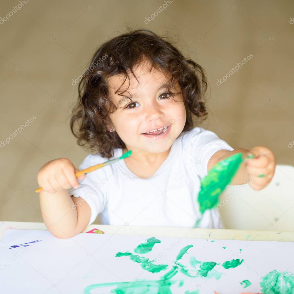 Adorable child painting fall leaves at table.