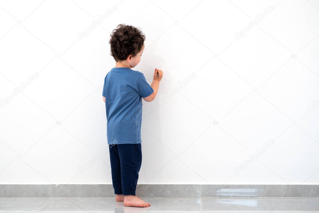 LIttle boy drawing on the wall.