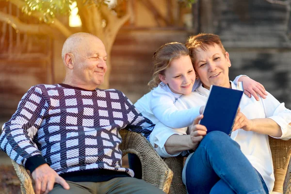 Прекрасна щаслива бабуся і дідусь читання онуці Книга в природі на заході сонця . — стокове фото