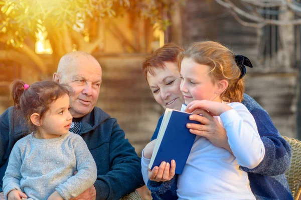 Красива Щаслива стара пара і онуки читають книгу разом в природі на заході сонця . — стокове фото