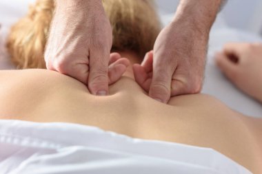 Erkek doktor ellerine yakın çekim. Kafkas Kadın Tıp Bürosu 'nda sırt masajı yaptırıyor. Genç bir kız spa salonunda erkek bir masözden vücut masajı alıyor..