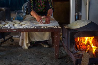 Yaşlı Arap kadın geleneksel bedevi mutfağı yemekleri pişiriyor - tabon ekmek ya da yassı ekmek. Arap kadınlarının ellerinin Taboon ekmeği ya da Laffa için taze hamur pişirmesine yakın durun. Orta Doğu ve İsrail düz ekmeği.