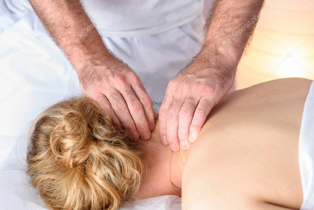 Close-up on the man doctor hands. Caucasian Woman Receiving Therapeutic Head Massage in medical office. A young girl receives a head massage in a spa salon from a male masseuse.