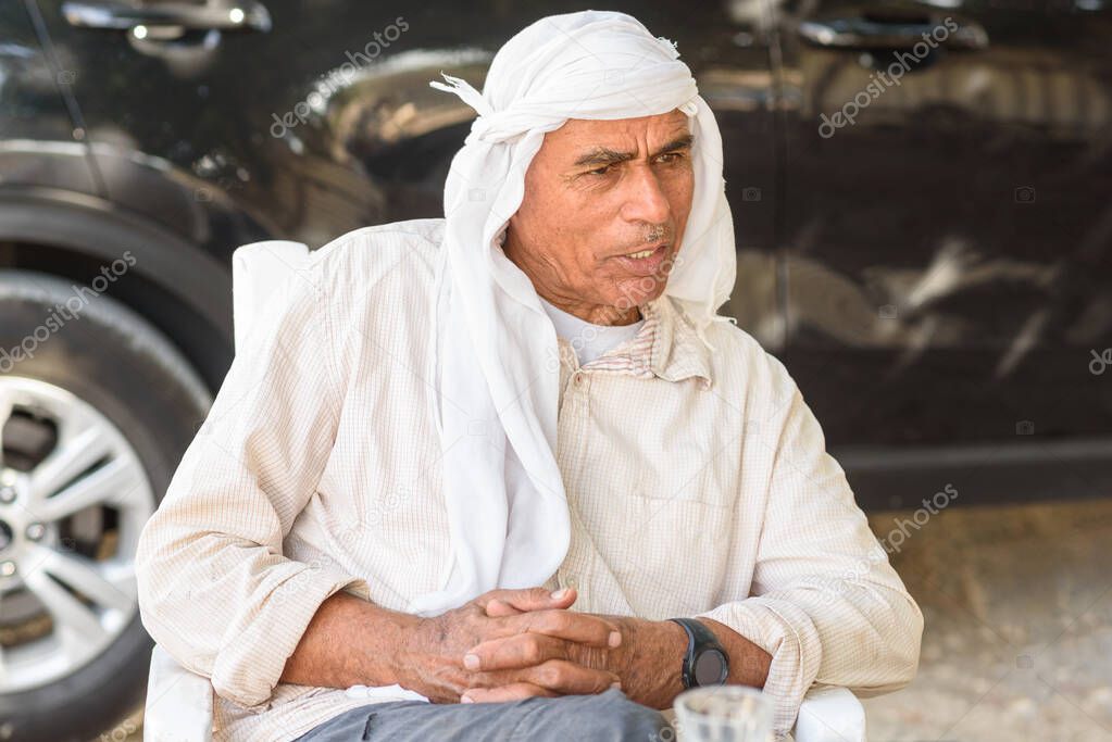 Old Arabic man in traditional clothes outdoor portrait. Serious Muslim Senior business man on a meeting.