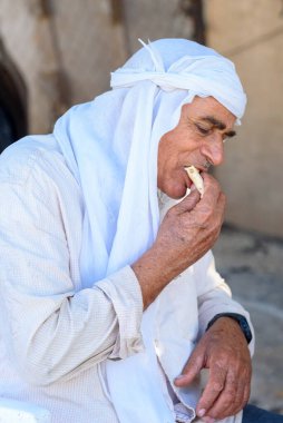 Ganj timsahı, keffiyeh veya kufiye 'deki Müslüman ihtiyarlar humus ve geleneksel Arap yemekleriyle birlikte tortilla dürümü veya pita ekmeği yerler..