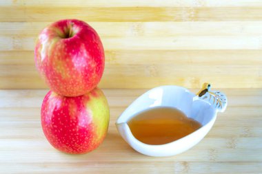 Ahşap masa arkasında bal ve elmalar.