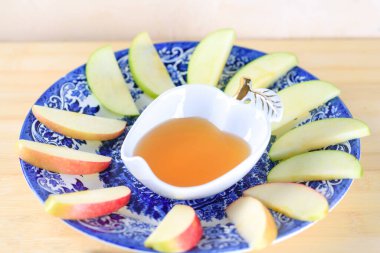 Yahudi bayramı, Rosh Hashana. Ballı ve ahşap masadaki elma dilimli. Yahudi Yeni Yılı boyunca Rosh Hashanah adetlerine uygun olarak bal sembolüne batırılmış dilimlenmiş elma yenir..