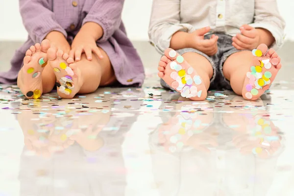 Маленькі дитячі ноги покриті різнокольоровими конфетті . — стокове фото