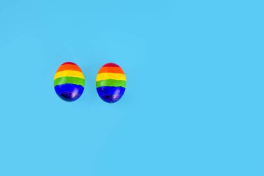 Lgbt çifti ailesi. Mavi arka planda gökkuşağı lgbt bayrağı renginde iki yumurta. Eşcinsel geçit töreni için yaratıcı fikir, LGBTQ seyahat, parti, homoseksüel evlilik, sevgililer günü, Paskalya. Boşluğu kopyala.