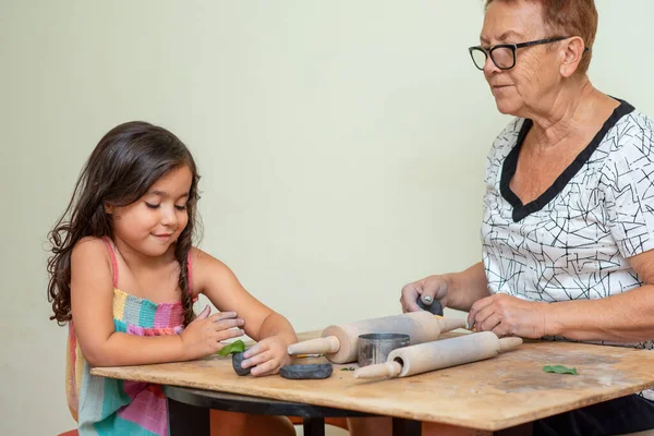 Старша жінка вчить дитину ліпити глиною . — стокове фото