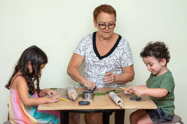 Старша жінка вчить дітей ліпити глиною . — стокове фото