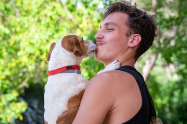 Yakışıklı genç adam köpeğini kollarında tutuyor..