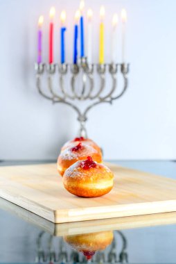 Hanuka kutlaması konsepti. Lezzetli çörekleri reçelli ve menoralı geleneksel şamdanlı yakından izleyin..