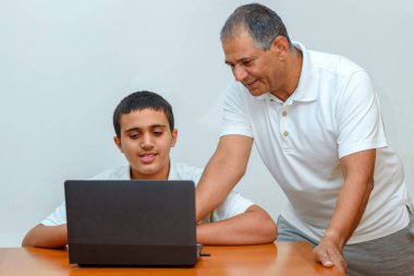 Mutlu aile, dizüstü bilgisayarda yaşlı büyükbaba ve torun. Yaşlı öğretmen ve genç öğrenci..
