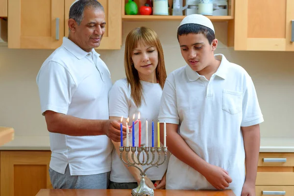 Pai judeu, mãe e filho adolescente acendendo velas Chanukkah em um menorah para férias — Fotografia de Stock
