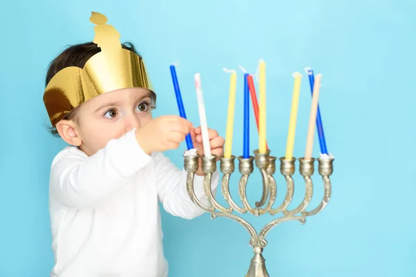 Kleine joodse jongen zet kaarsen op traditionele menorah. — Stockfoto
